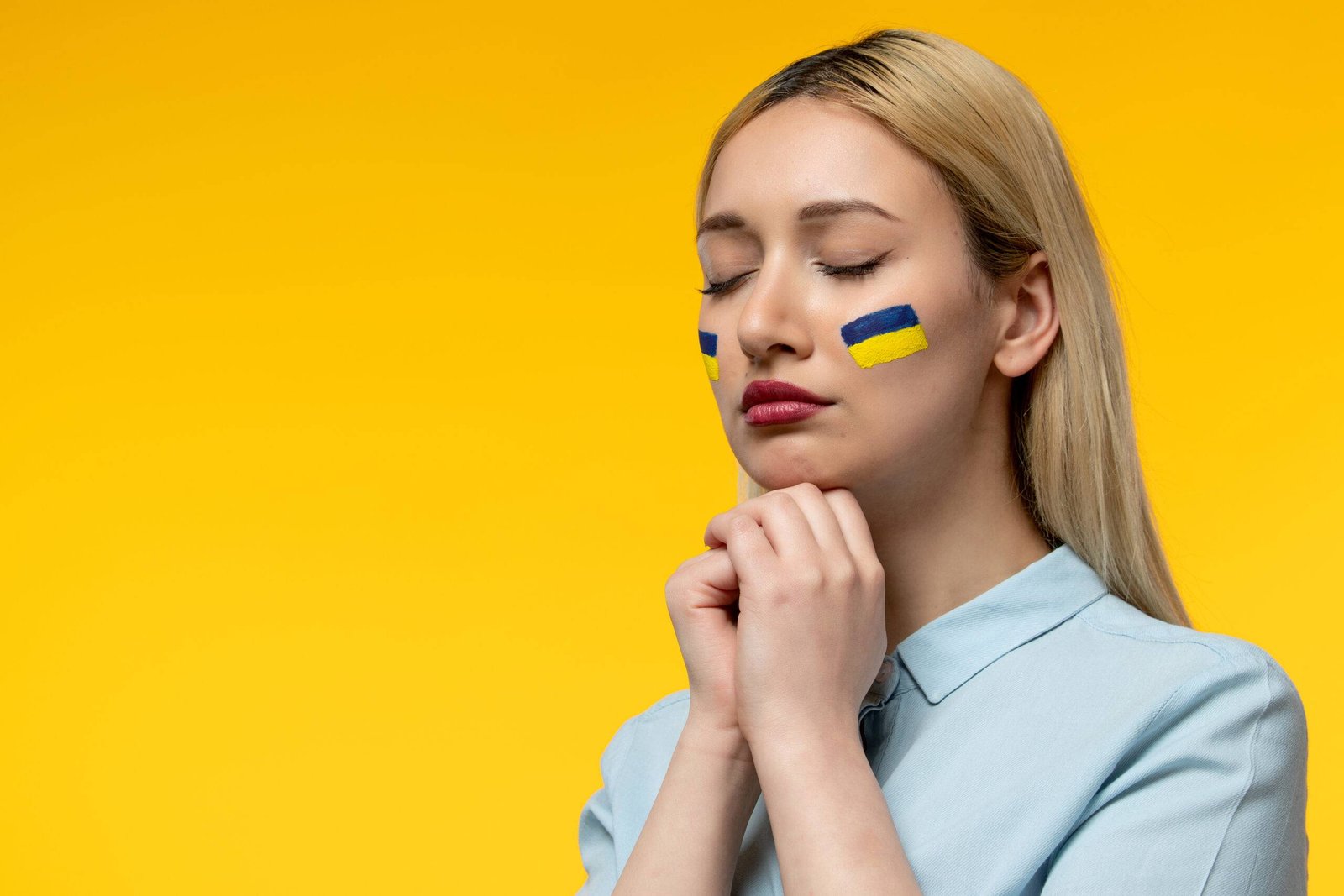 russian-ukrainian-conflict-young-cute-girl-with-ukrainian-flag-on-cheeks-praying-closed-eyes